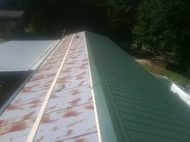 Old rusted panels beside newly installed green metal roofing — Wind Damage Roof Repair by Roofing Brothers in New Germany