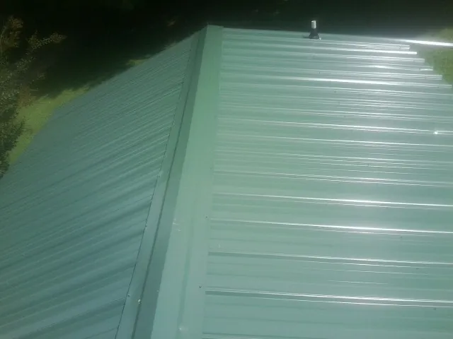 New green metal panels meeting at the ridge of a roof — Flat Roof Repair work by our crew in New Germany