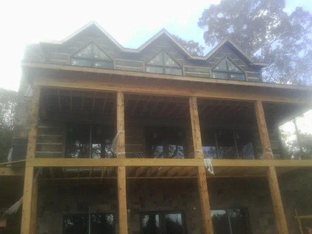Dormers and porch framing on a large log home under construction — Roof Coating work by our crew in New Germany