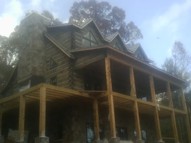 Stone chimney and dormers on a large log home with a timber porch in New Germany