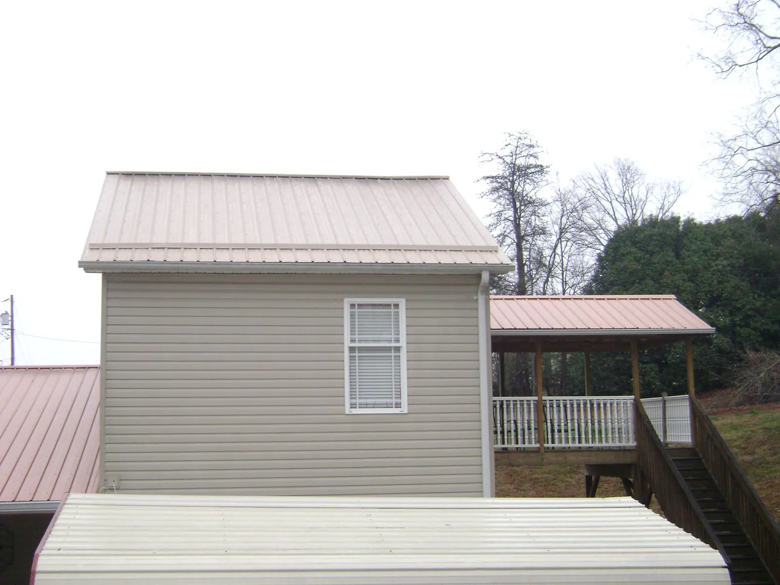 Tan metal roofs on a two story addition and attached porch, from a Roof Replacement job in New Germany